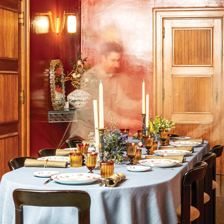 Dining table set for a meal with candles and decorative items in a warmly lit room.