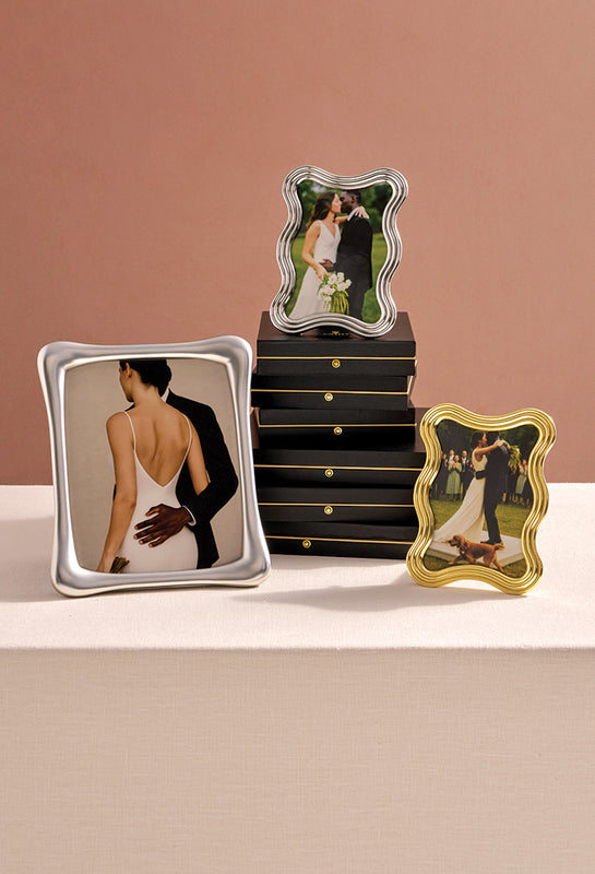 Three decorative photo frames with different designs on a beige surface.