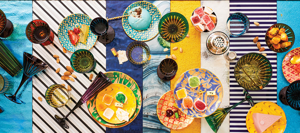 Collage of colorful tableware including plates, bowls, and glasses on a striped background.