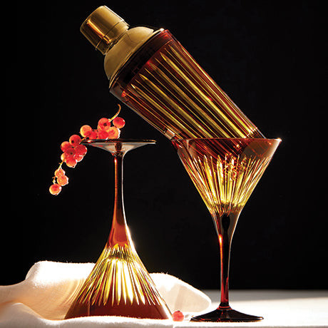 Gold cocktail shaker and glasses with red berries on a dark background