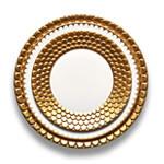 A place setting alternating white and gold plates sculpted with Aegean wave motif.
