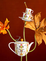 Decorative teapot and cups with floral design on a red background