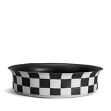 Black and white checkerboard glaze pattern on a low, round porcelain bowl with a flared rim shape. 