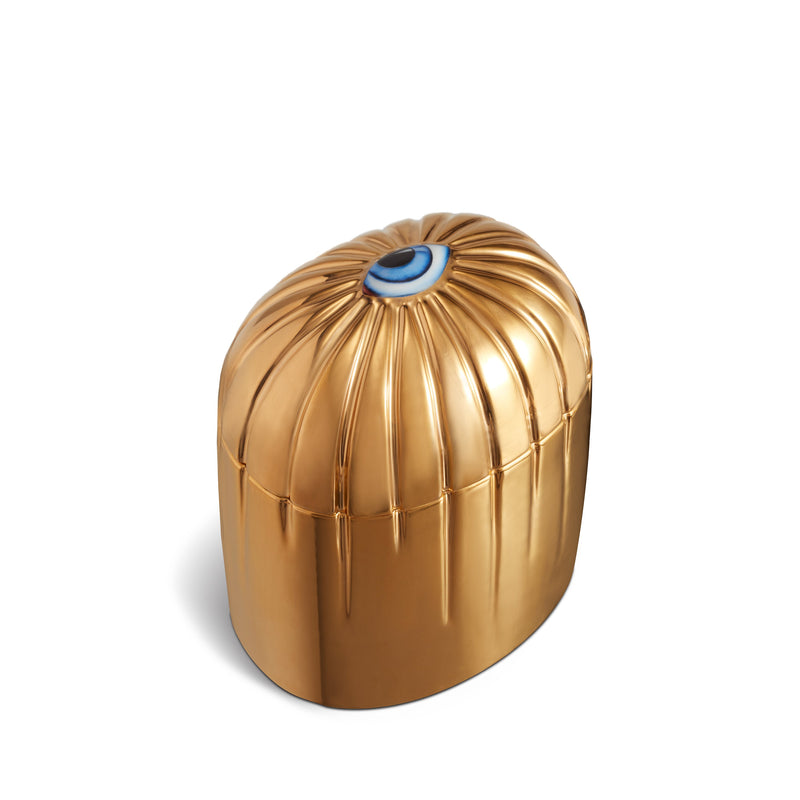 gold cylinder candle with gold details dripping from top eye motif
