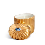 gold cylinder candle with one wick posed with its eye motif topper
