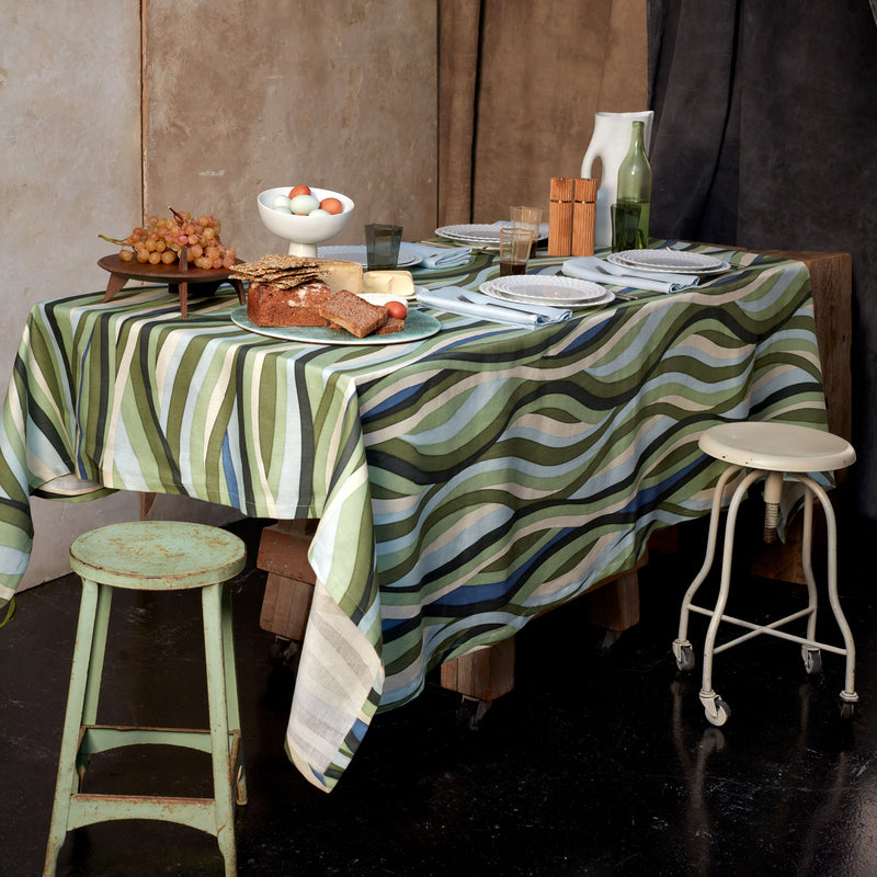 Tabletop with Linen tablecloth and napkins with an organic, undulating pattern in blue, green and ivory hues.