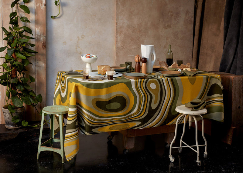 Table set with Terra bowl on stand, Terra leather and seafoam dinnerware, linen sateen green and yellow waves tablecloth