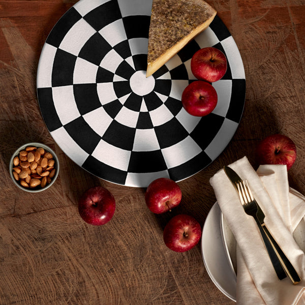  Black and white checkerboard pattern on a low, round porcelain platter on a wood tabletop