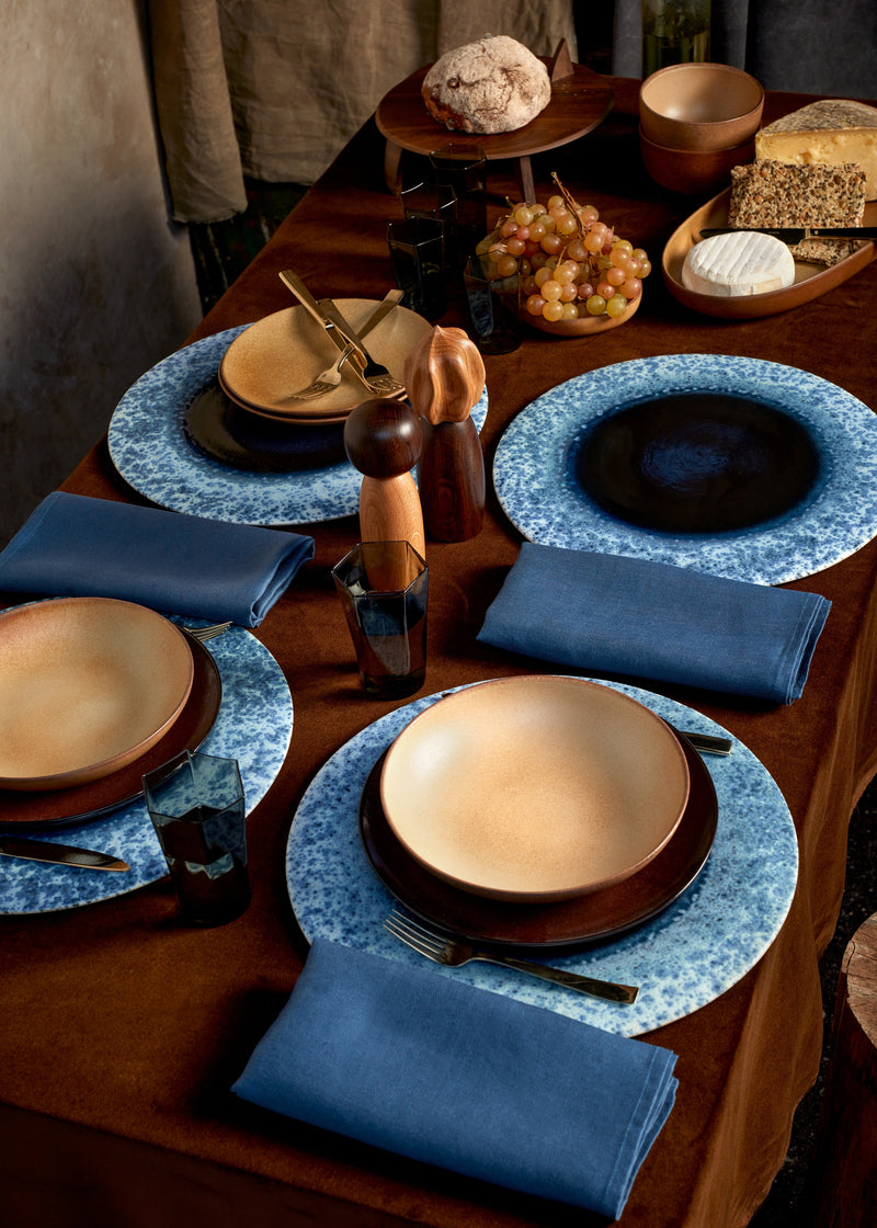 Blue round placemat set with Terra leather and wine glazed dinnerware