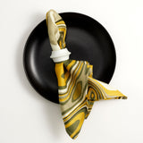 Terra iron glazed dinner plate, Terra porcelain napkin ring, Linen napkins with an organic, psychedelic pattern in muted green, yellow, brown and ivory hues.