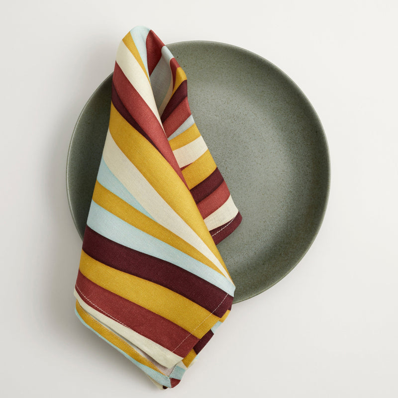 Terra seafoam glazed dinner plate and Linen napkins with an organic, undulating pattern in red, burgundy, blue, green and ivory hues.