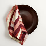 Terra wine glazed dinner plate, Linen napkins with an organic, psychedelic pattern in pink and red hues.